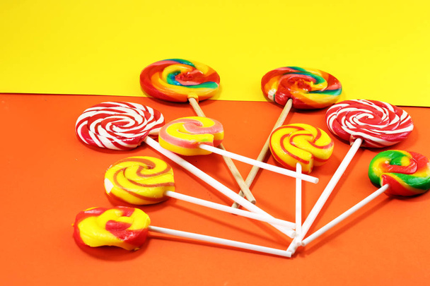 Lollipop op gele en oranje achtergrond. Lolly snoep - Foto, afbeelding