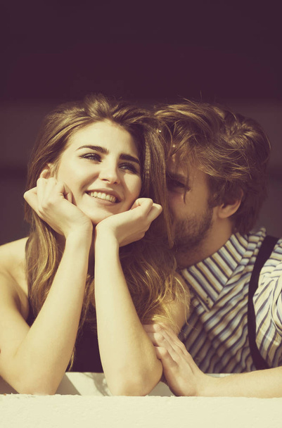 Handsome man whispering on ear to smiling pretty girl - Foto, Bild