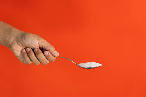 Hand holding a spoon full of sugar - Fotó, kép