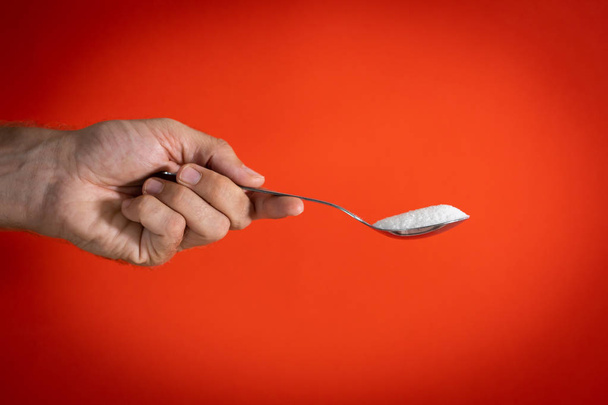 Hand holding a spoon full of sugar - Fotó, kép