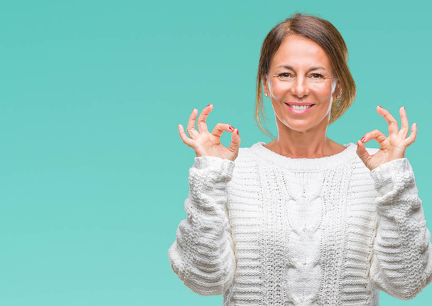 Старшая латиноамериканка средних лет в зимнем свитере на изолированном фоне расслабляется и улыбается с закрытыми глазами, делая жест медитации пальцами. Концепция йоги
. - Фото, изображение