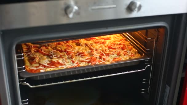 Lähikuva naisten avaaminen uuni keittiössä ja grillaaminen pizza tai vuoka
. - Materiaali, video