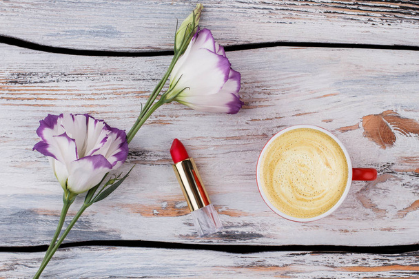Lisianthus-Blumen, Lippenstift und eine Tasse Cappuccino. - Foto, Bild