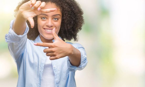 Young afro american woman over isolated background smiling making frame with hands and fingers with happy face. Creativity and photography concept. - Photo, image