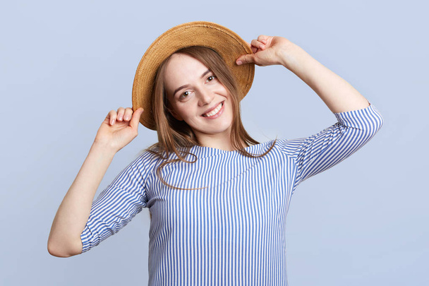 Headshot of adorable pretty young woman wears straw hat and striped blouse, being in good mood, rejoices coming vacations, going to spend them in tropical country abroad together with boyfriend - Fotó, kép