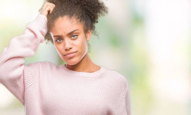 Young afro american woman wearing winter sweater over isolated background confuse and wonder about question. Uncertain with doubt, thinking with hand on head. Pensive concept. - Photo, Image