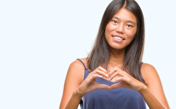 Young asian woman over isolated background smiling in love showing heart symbol and shape with hands. Romantic concept. - Foto, immagini