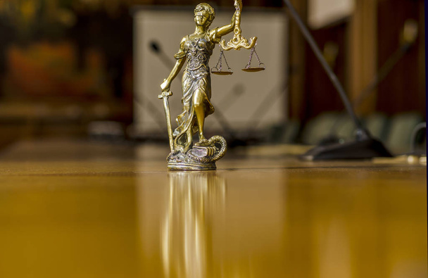 Άγαλμα του Γιουστίτια στο τραπέζι με τα μικρόφωνα στην αίθουσα συνεδριάσεων - Φωτογραφία, εικόνα