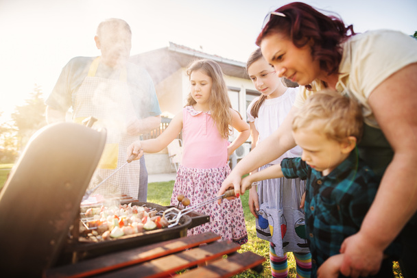 feliz familia cocina en la parrilla al aire libre - Foto, imagen