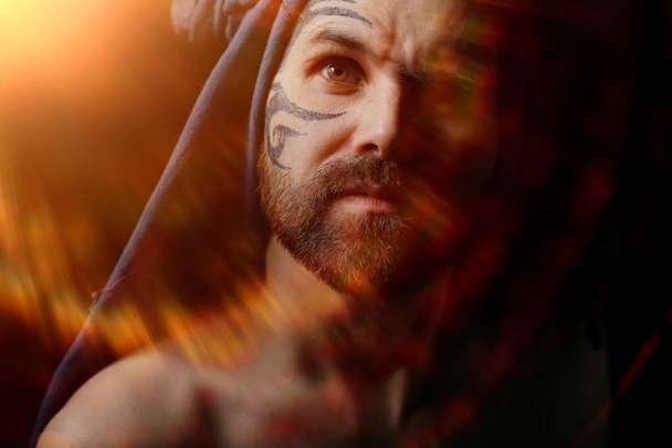 portrait of brutal bearded man with tattoo on face - Foto, Imagen