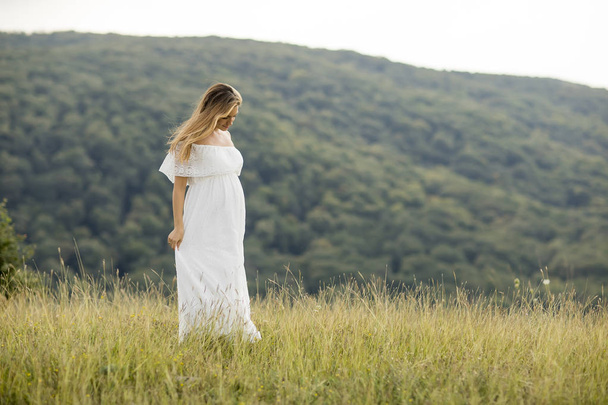 Giovane donna incinta rilassante all'aperto nella natura durante la giornata estiva
 - Foto, immagini