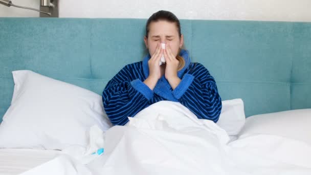 Vídeo 4k de una joven enferma acostada en la cama, usando pañuelos de papel y aplicando aerosol nasal
 - Imágenes, Vídeo