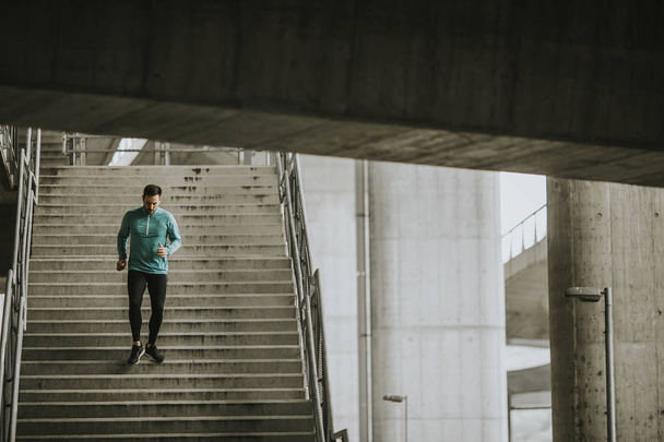 Νεαρός άνδρας τρέχει γρήγορα κάτω από τις σκάλες στην πόλη - Φωτογραφία, εικόνα