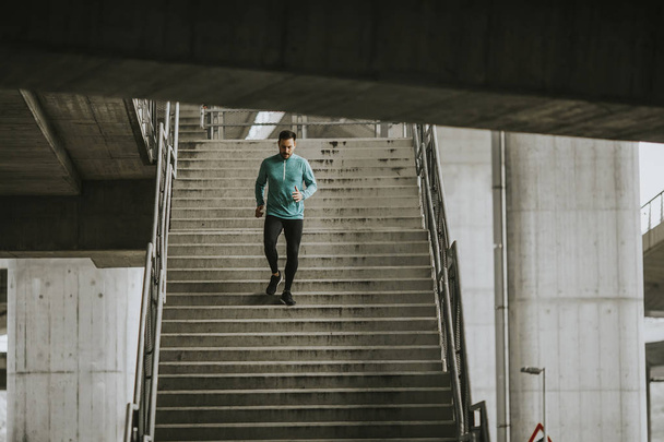 Nuori mies juoksee nopeasti alas portaita kaupungissa
 - Valokuva, kuva