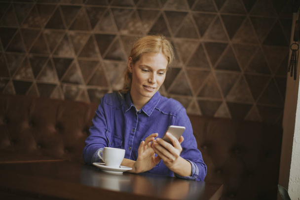 Hezká mladá blonďatá žena s mobilním telefonem v kavárně - Fotografie, Obrázek