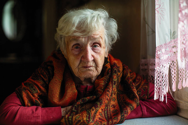 Portret van een oudere vrouw van vermoeidheid in haar huis.  - Foto, afbeelding