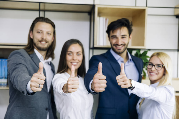 Portrait de jeunes gens d'affaires prospères montrant pouce vers le haut signe dans le bureau
 - Photo, image