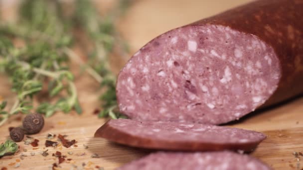 ハーブの横にまな板の上のナイフでスライスされる美味しい肉のデリカテッセン - 映像、動画