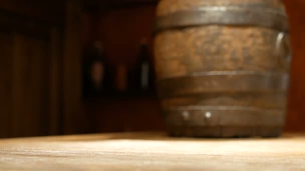 La mano humana pone una taza de cerveza de madera vieja sobre la mesa en el fondo de un pequeño barril para bebidas. Platos en el pub
. - Imágenes, Vídeo