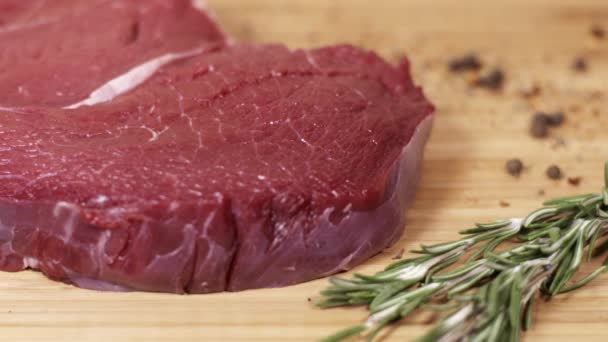 Stück rohes rotes Steak auf dem Tisch mit Kräutern und Gewürzen - Filmmaterial, Video