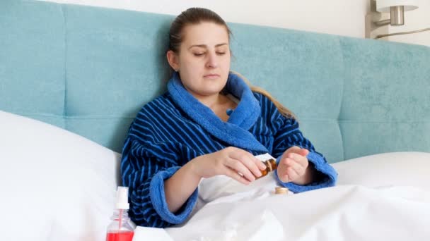 4 k video van jonge vrouw badjas gevoel ziek in bed liggen en drinken pillen - Video