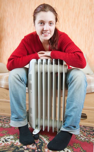 Girl is sitting by a oil heater - Foto, afbeelding