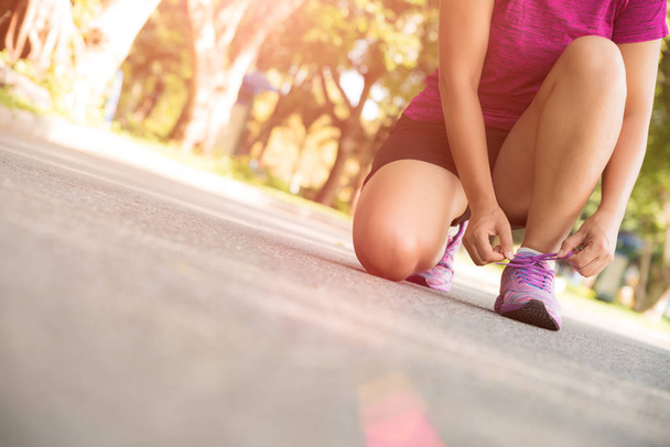 Běžecká obuv - detailní ženy zavazování tkaniček. Ženské sportovní fitness běžec připravuje na běhání v zahradní backgroound - Fotografie, Obrázek