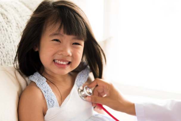 Γιατρός εξετάζει ένα κοριτσάκι με στηθοσκόπιο. Ιατρική και υγειονομική περίθαλψη έννοια. - Φωτογραφία, εικόνα