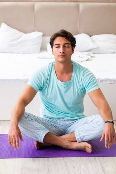 Young man in pajamas doing morning exercises  - Photo, Image