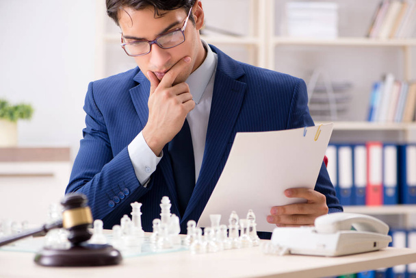 Giovane avvocato che gioca a scacchi per allenare la sua strategia giudiziaria e tattici - Foto, immagini