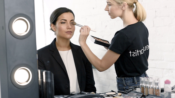 jonge zakenvrouw krijgen make-up gedaan door make-up artiest - Video