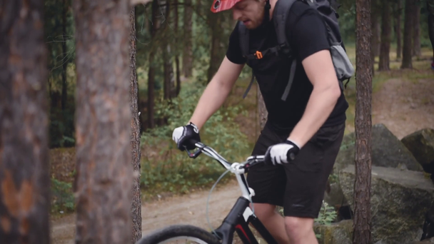 young trial biker in helmet riding bicycle in pine forest - Felvétel, videó