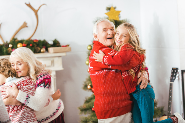happy grandparents embracing with kids on christmas at home - Foto, afbeelding