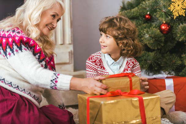 grandmother and her grandson with christmas gifts looking at each other - Foto, Bild