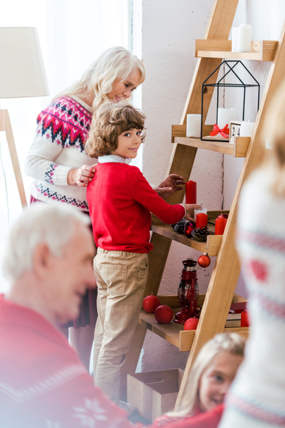 adorable little kid decorating living room for christmas with his family - Foto, Imagem