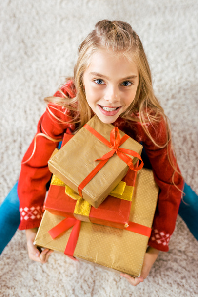 vue grand angle de bel enfant heureux assis sur le sol avec pile de boîtes-cadeaux de Noël
 - Photo, image