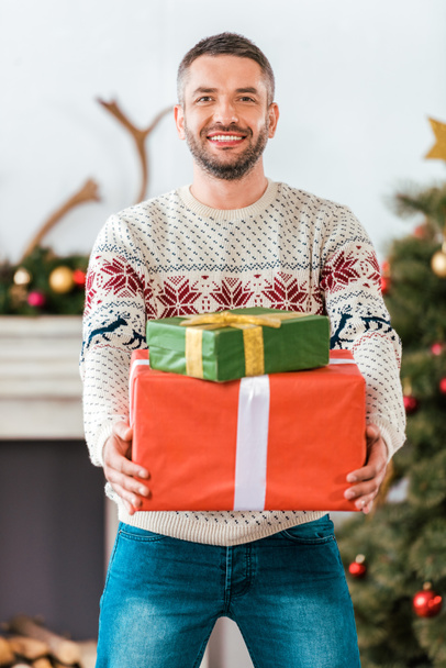 happy bearded man in christmas sweater with gift boxes looking at camera - Foto, Imagem