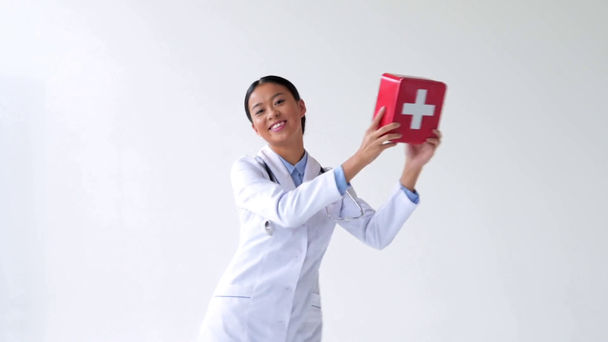 счастливый молодой азиатский врач танцует с аптечкой на белом
 - Кадры, видео