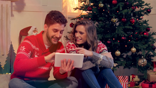 Happy νεαρό ζευγάρι χρησιμοποιώντας tablet μαζί τα Χριστούγεννα - Πλάνα, βίντεο