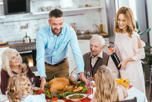smiling family with turkey celebrating thanksgiving day at home - Zdjęcie, obraz