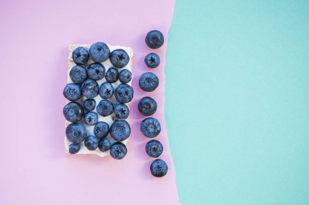 Blueberry boşaltmak pembe ve mavi zemin üzerine ile lezzetli sağlıklı sandviç. Sağlıklı gıda kavramı. - Fotoğraf, Görsel