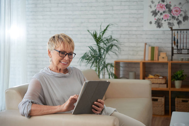 Улыбающаяся пожилая женщина с помощью приложения на планшетном компьютере
 - Фото, изображение