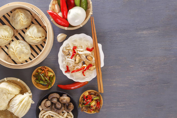 Блюда китайской кухни в ассортименте. Паровые пельмени, лапша, салаты, овощи, грибы, морепродукты. Вид сверху. Копирование пространства
 - Фото, изображение