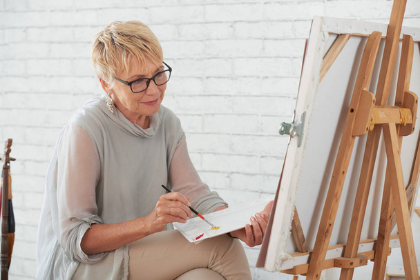 Seniorin malt im heimischen Atelier auf Leinwand - Foto, Bild
