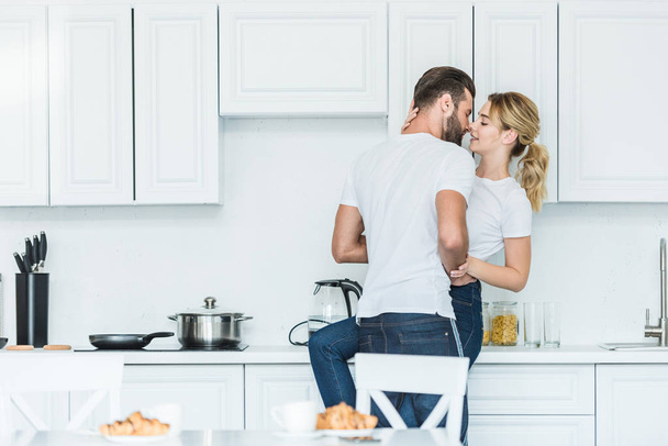 beautiful young couple in love kissing in kitchen at morning - Foto, afbeelding