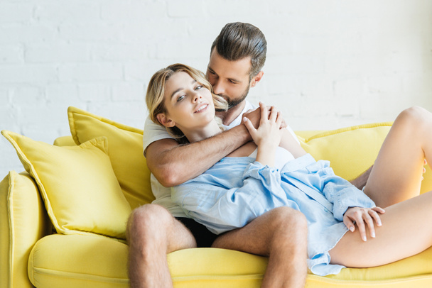 handsome young man in underwear hugging attractive girlfriend at home - Photo, Image