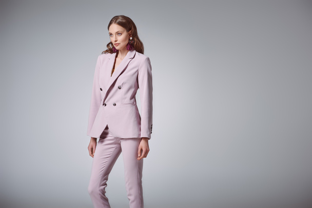 attractive woman in fashionable pink suit looking away isolated on grey - Photo, Image