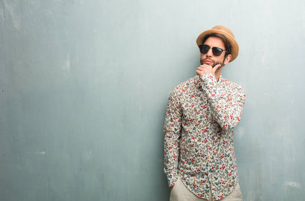 Jeune voyageur homme portant une chemise colorée doutant et confus, pensant à une idée ou inquiet de quelque chose
 - Photo, image