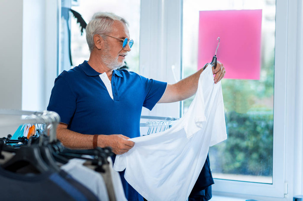 Positive grey haired man choosing stylish clothes - Foto, imagen