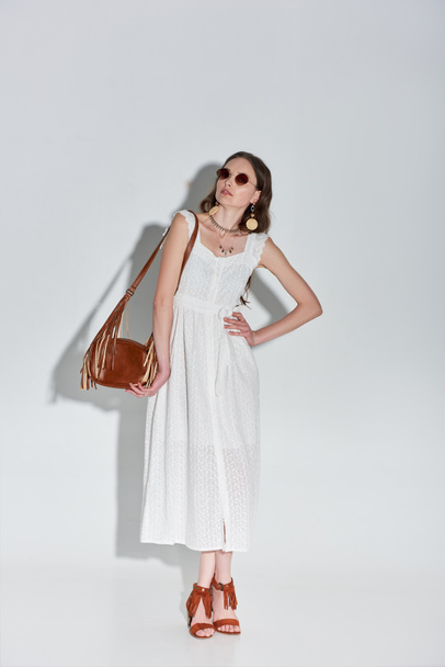 kaunis tyylikäs nainen muodikas valkoinen mekko poseeraa käsi vyötäröllä harmaa
 - Valokuva, kuva